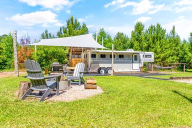 Gravel campsite with tent platform and picnic/fire area — clear view of a typical glamping pitch; comes from the property’s glamping gallery (87_tg2_5550).