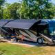 Close view of an RV pitch with awning, hookups and picnic setup demonstrating typical full-hookup RV accommodations on the property.