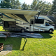 Clear on-site photo of an RV parked at a grassy campsite with picnic table, fire ring and utility pedestal visible — good overview of RV sites and site amenities from the campground’s homepage.