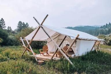Glamping-style tent on a raised platform set in natural vegetation — shows on-site lodging/guest accommodation option promoted on the property.