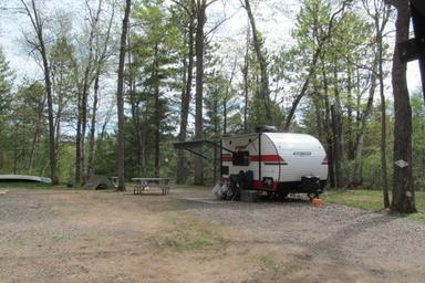Individual RV pitch with picnic table and canoe visible nearby — good representation of a typical RV campsite on the property (from photo gallery).