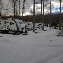 Shows several RVs on sites in a wooded area (winter/snow) — useful seasonal view of RV pitches and site spacing (source page: homepage https://shadybrookcg.com/).
