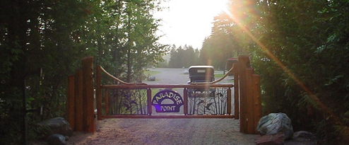 Entrance gate with a visible Paradise Point sign set in a wooded drive — useful for identifying the property's entrance and arrival experience (homepage header image).