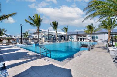Ground-level pool photo showing pool deck, water features and clubhouse in background — useful for guests viewing recreational facilities (gallery).