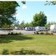 Park overview showing multiple RVs parked along paved sites with adjacent lawn and picnic tables — strong overall view of the campground grounds and amenities.