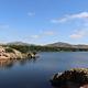 The Wichita Mountains line the horizon beyond the pink granite shore of Quanah Parker Lake.