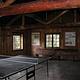Ping-pong table in dimly lit large room with log rafters and benches.