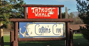 Entrance sign for 'Captain's Cove' on a landscaped grassy area — identifies property entry and location on the grounds.