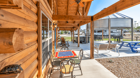 Covered porch and outdoor seating area at the clubhouse with park infrastructure visible beyond — useful to show on-site amenities and guest gathering spaces (homepage photo).