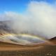 view of crater, orange and black cinder hills with clouds and a low rainbow 