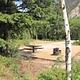 Campsite with trees, picnic table, fire pit, mountain in background