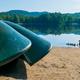Shown are green canoes near the water. Ducks are also shown swimming in the lake.