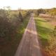 Aerial/drone-style view down a long internal campground road with trees and open fields on either side — clear overview of property layout. Source: Gallery page of the campground website (supports on‑site photo).
