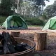 Campsite with metal fire ring in the foreground and two green tents in the background.