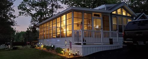 Exterior evening view of a lakeside cottage with lit windows and landscaped yard — good to illustrate rental cottage accommodations (file shown on the site’s main page for the property).