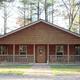 Clear frontal shot of one of the property's wood cabins with porch and surrounding pine trees — useful for lodging/unit gallery. Image comes from the site's gallery/background images showing the cabin used to illustrate accommodations.