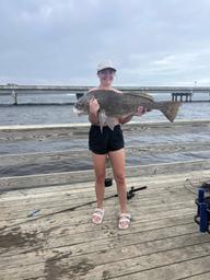 Dock/pier scene with a person holding a large catch; shows the waterfront pier and immediate shoreline amenities used by guests (good for illustrating fishing and pier access on site).