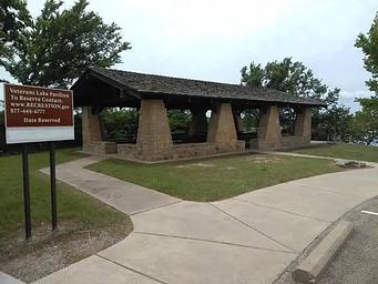 Veterans Lake Pavilion showing the sign post and paved sidewalk from parking area