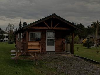 Cabin exterior photo showing a wooden rental cabin with porch and picnic table — represents the campground's cabin lodging. Labeled under Cabins on the site.