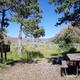 Clearwater Campground site 1 which shows a picnic table and bear box nestled among trees. There are mountains and blue sky in the background.