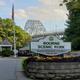Clear photo of the park entrance sign with the Bourne Bridge visible in the background — establishes property identity and location on the waterfront; image appears on the site homepage.