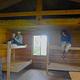 Gut Island Cabin 1 interior with two people reading books on the top of wooden bunks
