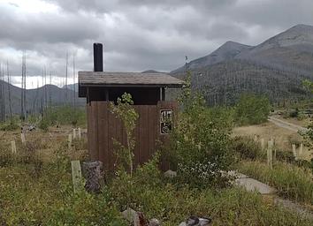 Outhouse on cloudy day with mountain in background