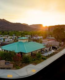 Vertical crop of the RV resort clubhouse and adjacent RV sites at sunset, showing site details, walkways and landscaping — complements the panoramic views with a closer perspective.