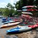 Kayaks and boats stacked along the riverbank showing equipment rental/launch area — useful facility image and matches floating page context on the site.