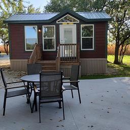 Small cabin exterior (deluxe cabin) with patio furniture visible — matches the site’s 'deluxe cabins' / accommodations photos on the campground page.