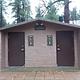 Accessible two vault toilet building with concrete slab in front located behind main building. 