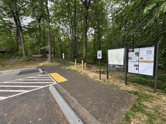 Handicapped parking and a paved walkway beside information signs in a forest