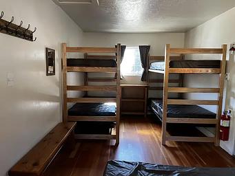 Bedroom showing double bed, two sets of bunkbeds and bench.