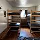 Bedroom showing double bed, two sets of bunkbeds and bench.