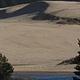 Shore pines with sand dunes and conifer covered hills in background.