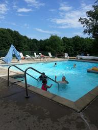 Photo of the heated outdoor pool with lounge chairs and surrounding trees — depicts a key on-site facility. Comes from the site's Facilities page, confirming it’s a campground amenity.
