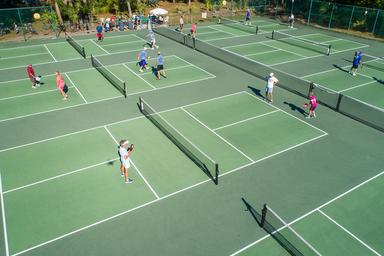 Overhead view of multiple pickleball courts with players — represents the resort’s on-site sports facilities (site advertises numerous pickleball courts).