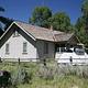 Cabin in meadow with tent in the split rail fenced yard and trees in the background