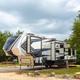 Large fifth-wheel rig on a paved pad with picnic table and trees — another clear example of RV accommodation style at the park.