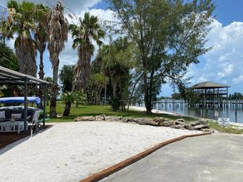Sandy shoreline and palm trees with dock/pavilion visible — good scenic view of property shoreline and waterfront features (from homepage/amenities images).