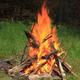 Close photo of a campfire on grass — shows on-site recreation/camping activity and matches Recreation page content.