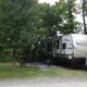RV parked at a gravel/grass site with picnic table and awning extended — representative photo of RV pitch layout and site amenities found on the campground pages.