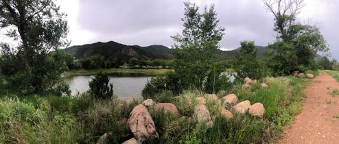 Panoramic lakeside scene with dock and visible campsites/cleared areas across the water — illustrates waterfront amenities and setting; appears on the home page background images.