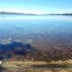 Clear Lake with stones, mountains and trees visible off in the distance.