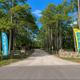 Gravel tree-lined entrance drive with welcome banners — useful exterior shot illustrating campground access and setting.