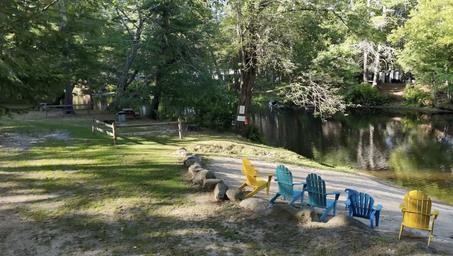 Sandy waterfront area with colorful Adirondack chairs facing a calm pond/river — good scenic feature of the campsite's water access (matches multiple gallery images on the site).