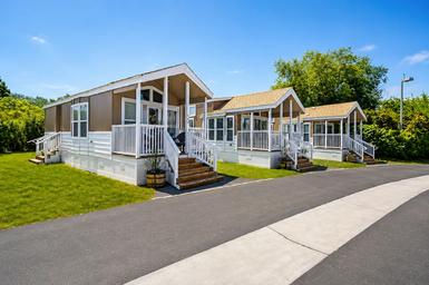Exterior shot of three cabin units on paved lot with porches and landscaping — shows the cabin accommodation style on site (gallery page source).