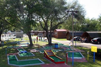 Miniature golf course and nearby cabins/play area — shows another on-site recreational feature and cabin accommodations visible on the campground's activities gallery.