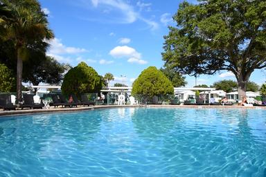 Large sparkling pool with lounge chairs and RVs visible in the background — clearly shows the on-site pool amenity referenced on the site.