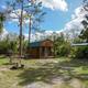 Clear exterior view of a campsite cabin with picnic table, fire ring and surrounding palms — matches the 'Cabins' page context on the property website showing on-site cabins and grounds.